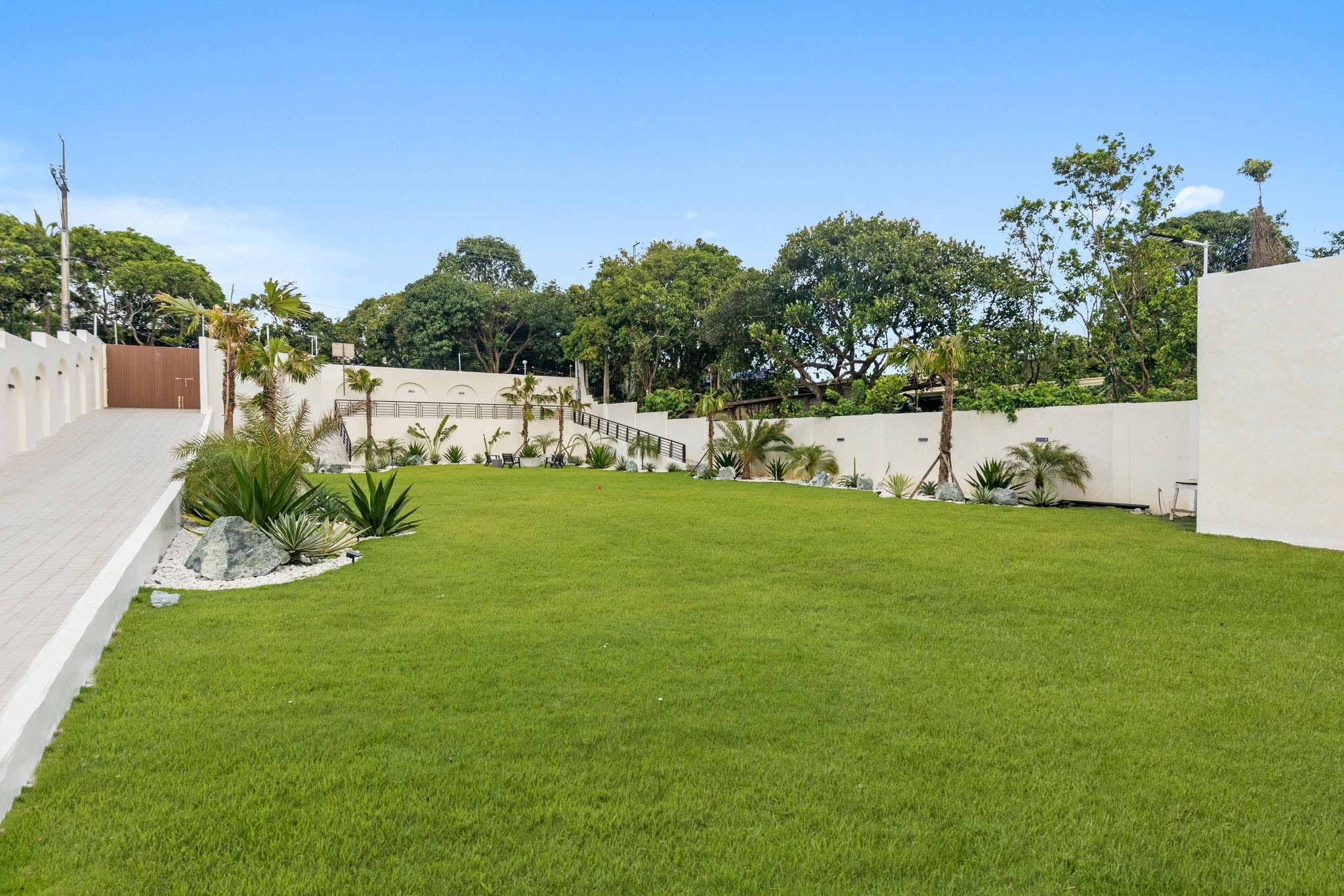 The open garden lawn at Villa Agave, framed by white walls and palms